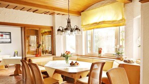 A dining area with a large wooden table, wicker chairs, and a chandelier. - Landhotel Sonnenhof (Siebeldingen)