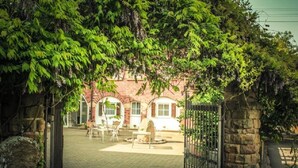 A brick building with arched windows and a paved courtyard. - Landhotel Sonnenhof (Siebeldingen)