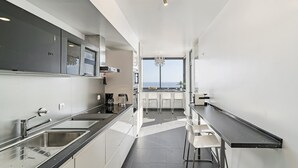 Une cuisine moderne dotée d’un long comptoir, d’appareils électroménagers en acier inoxydable et offrant une vue sur l’extérieur.