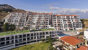 Un complexe hôtelier moderne comprenant plusieurs étages, des balcons et un espace piscine sur le toit.