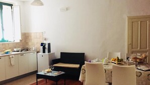 Ein kompakter Wohnbereich mit Küchenzeile, Essbereich mit Tisch und Stühlen sowie einer Couch.