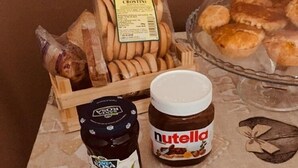Ein Tisch mit verschiedenen Speisen, darunter Brot, Nutella und Marmeladengläser.