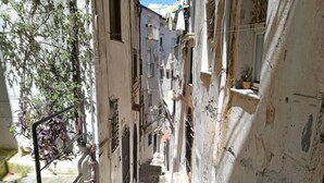 Eine enge, sonnendurchflutete Treppe zwischen Gebäuden mit deutlichen Gebrauchsspuren, die zu einer Tür oben führt.