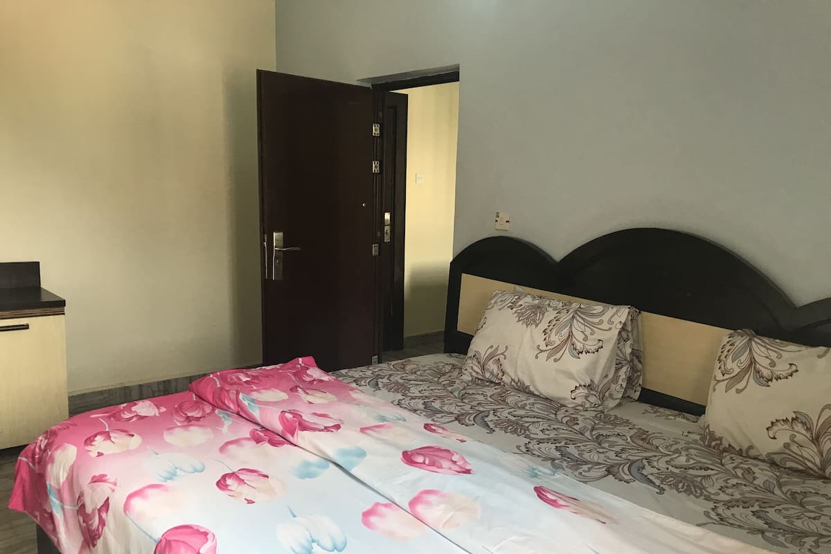 A bedroom with a bed, a nightstand, and a door.