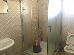 A bathroom with a glass-enclosed shower, a sink, and a toilet. - PennyHill Suites and Resorts (Enugu)