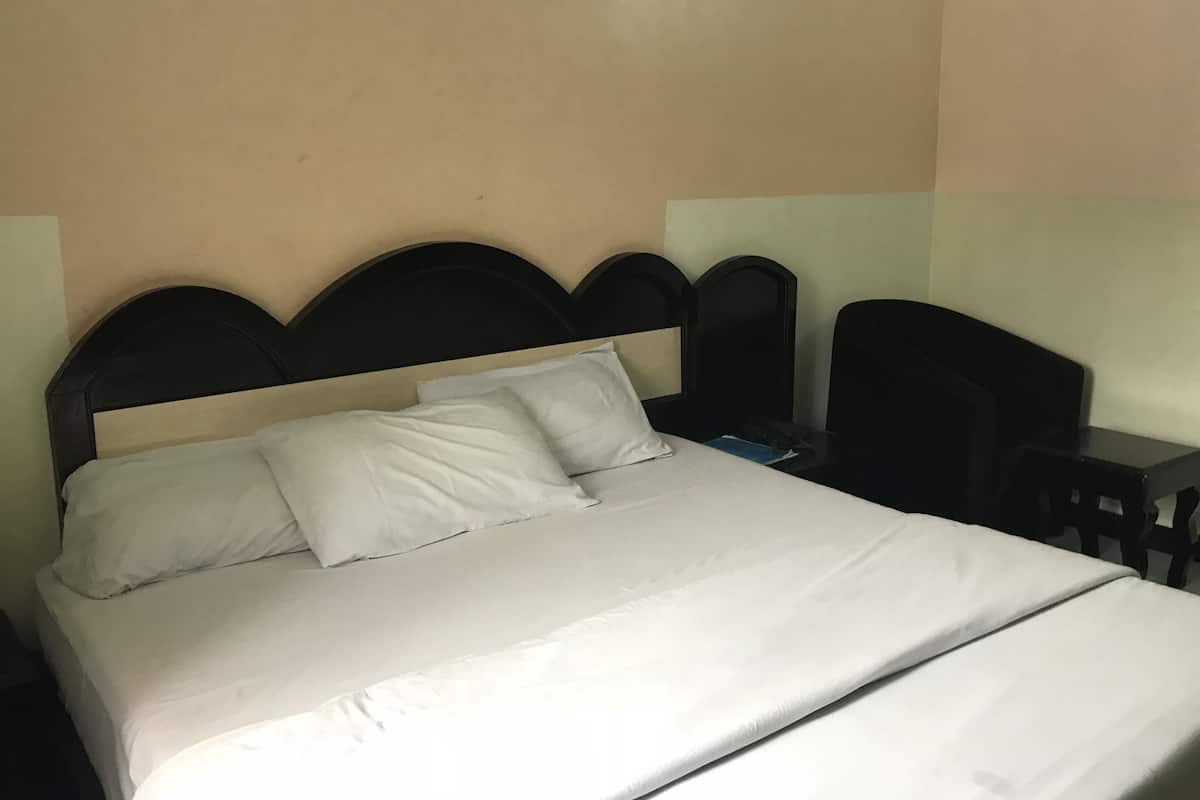 A bed with a headboard, a bedside table, and a chair.