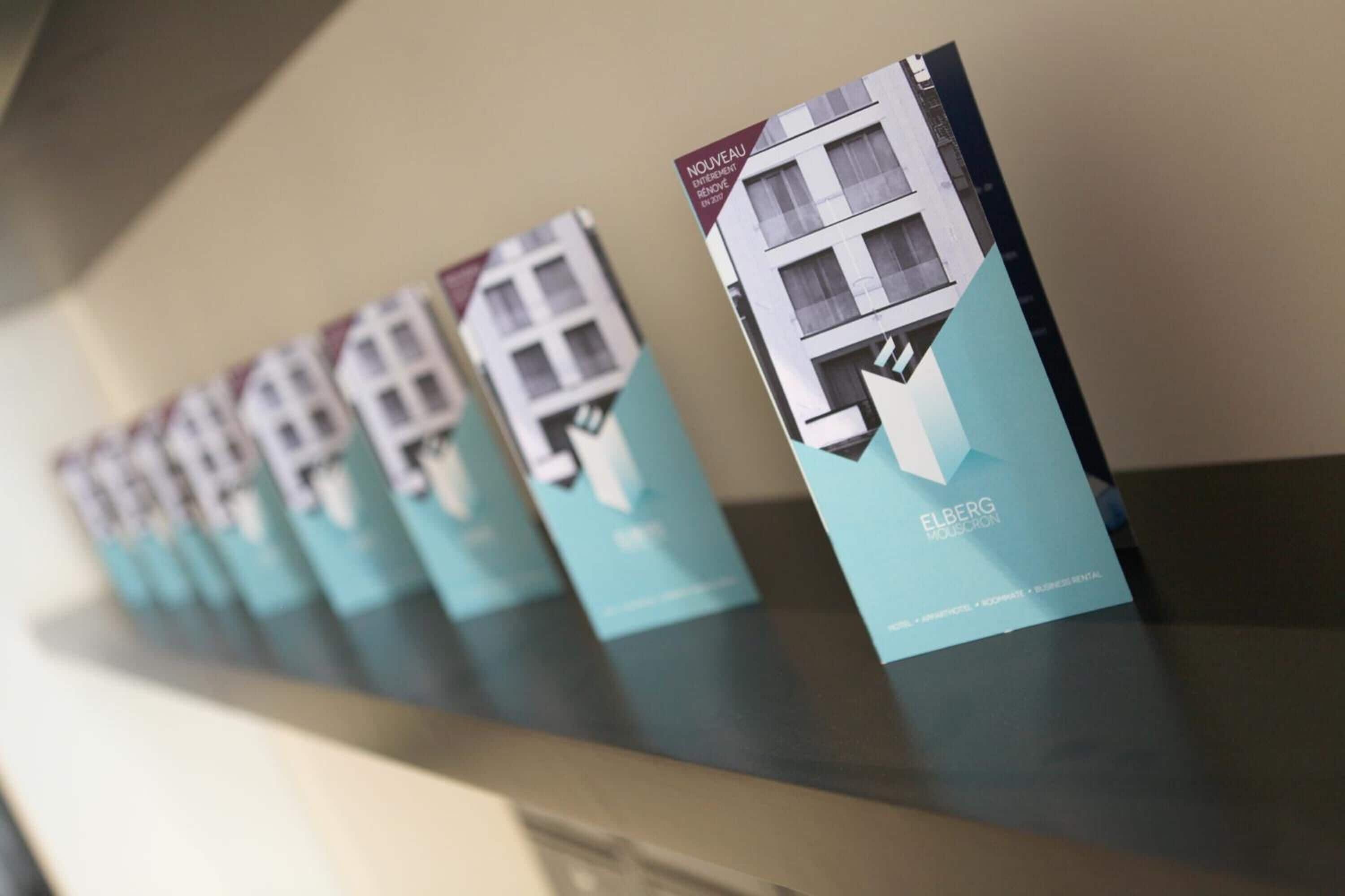 A row of brochures for a hotel, each featuring a building facade and the hotel's name.