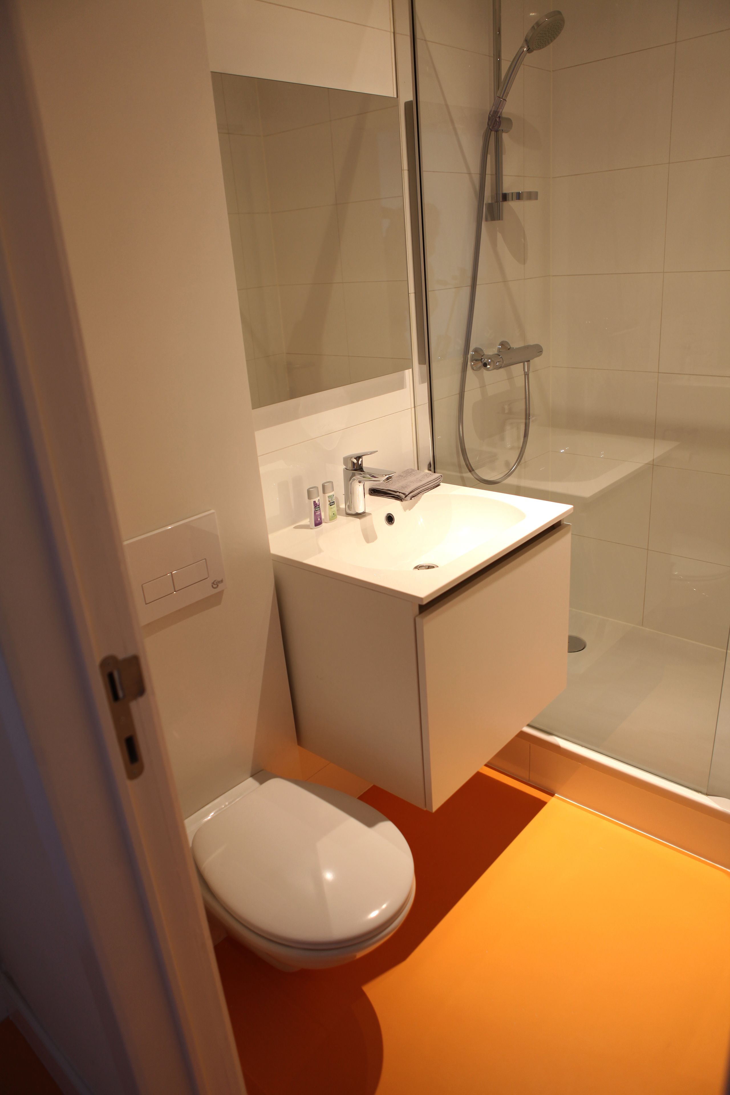 A modern bathroom with a toilet, sink, and shower.