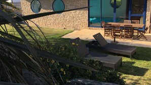 Un edificio de piedra con piscina, zona de estar al aire libre y césped cuidado.
