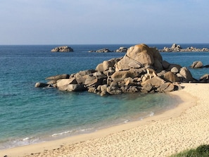 A beach with large rocks and clear blue water.