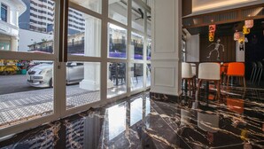 Eine Hotelhalle mit einer großen Glasdoor, die nach draußen führt, einem Marmorboden und einer Skelett-Dekoration an der Wand.