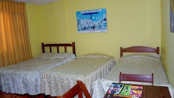 Una habitación con dos camas individuales, una silla de madera, una mesa con un libro y un cartel en la pared.