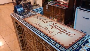 Una reception con un cartello che riporta 'Hostal Iguique' e 'Gima + Peri'.