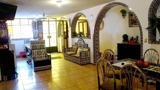 Un'area pranzo con pavimento piastrellato, un divano e un tavolo da pranzo con sedie.