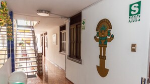 Un corridoio con un murale raffigurante una figura, un segnale di uscita verde e un cartello che indica un'area di sicurezza.