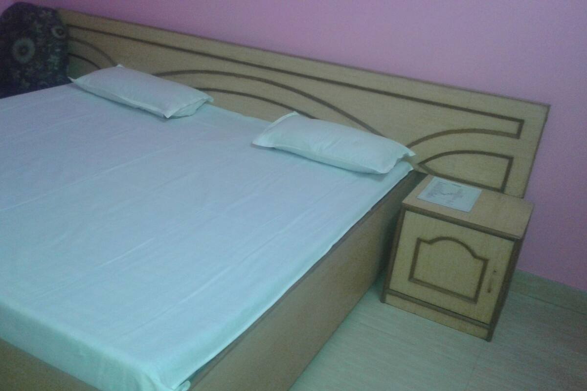 A bed with a wooden headboard, two pillows, and a nightstand with a small drawer.