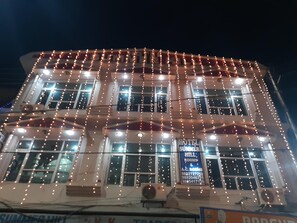 A hotel with multiple floors, string lights, and a sign advertising rooms and contact numbers. - Hotel summer Hill (Nahan)