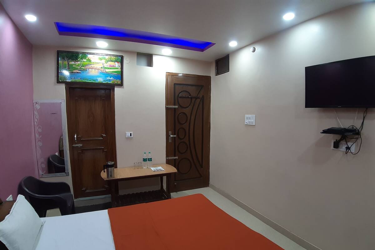 A hotel room with a bed, a TV mounted on the wall, a desk with a chair, and a door with a decorative design.