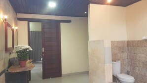 A hallway leading to a bathroom with a toilet and a sink. - A Newly 1-Bedroom House with Open Kitchen Overlooking to Garden (Amed)