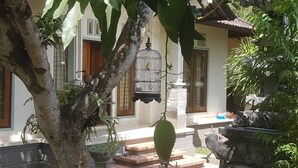 A traditional house with a tiled roof, a birdcage hanging from the ceiling, and a stone water feature. - A Newly 1-Bedroom House with Open Kitchen Overlooking to Garden (Amed)