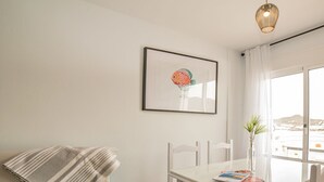 Een eetruimte met een witte tafel, stoelen en een lijst met een foto aan de muur.