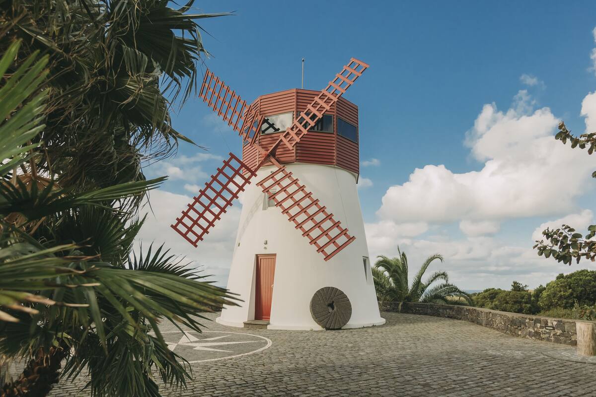 A windmill with a red and white structure, a door, and a circular window.