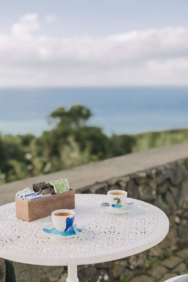 Una mesa metálica blanca con dos tazas de café y una caja de pañuelos.