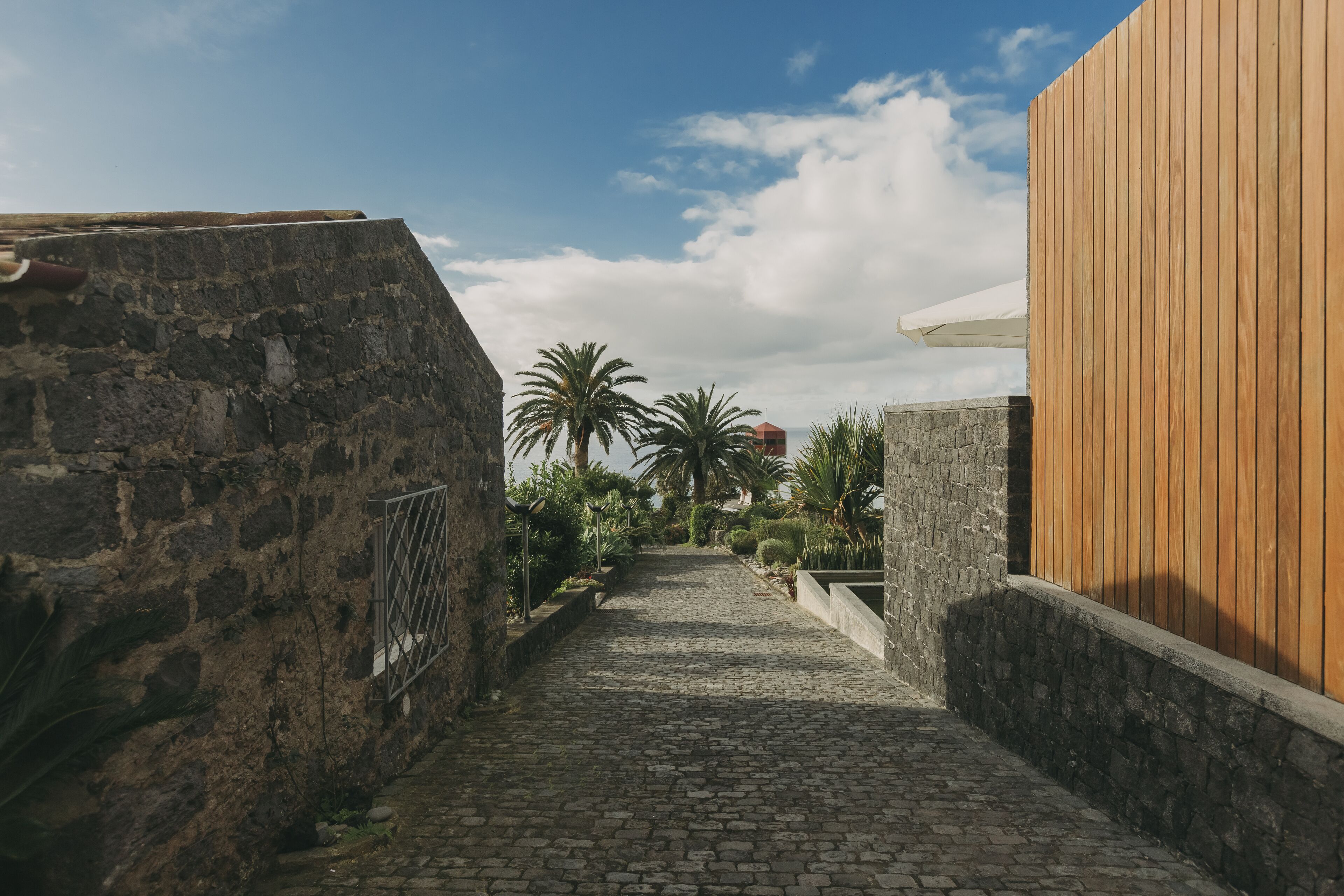 A cobblestone pathway leading to a wooden building with stone walls.