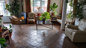 A living room with a glass coffee table, wicker chairs, a sofa, and multiple potted plants. - Alojamiento la Pedriza (Manzanares el Real)
