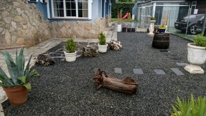 A gravel courtyard with potted plants, a wooden log, and a stone wall. - Alojamiento la Pedriza (Manzanares el Real)