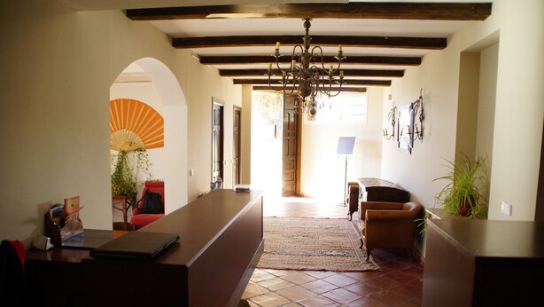 A spacious living area with a tiled floor, a wooden bench, a red chair, and a chandelier. - Alojamiento la Pedriza (Manzanares el Real)