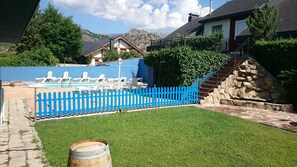 Zona de piscina con sillas de descanso y una valla azul.