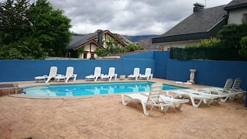 Una piscina al aire libre de temporada, tumbonas