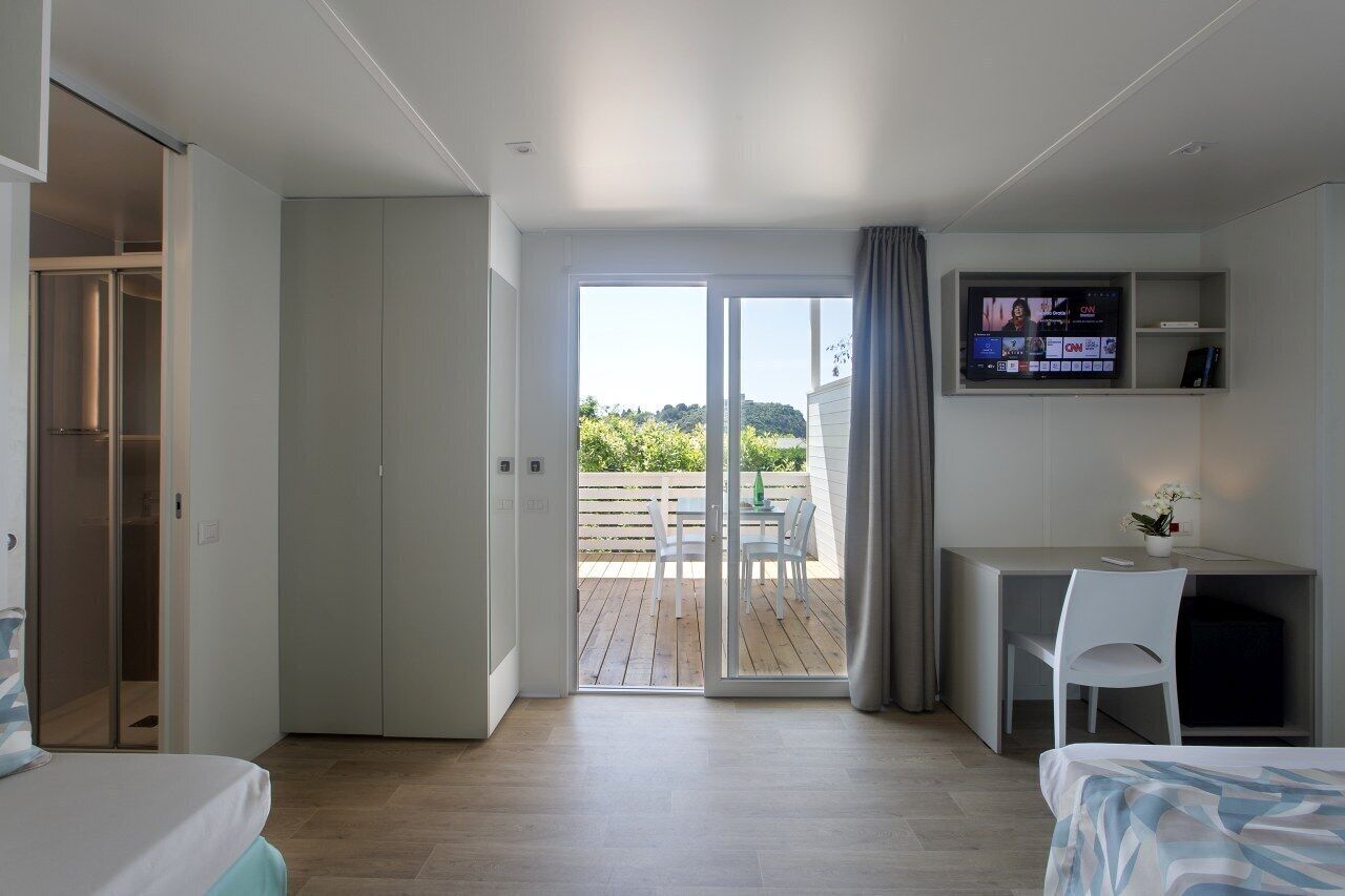Una camera d'albergo moderna con un balcone, una scrivania e una TV.