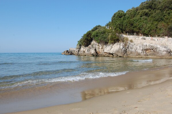 Aan een privéstrand, wit zand, ligstoelen, parasols