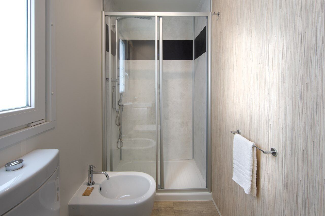A modern bathroom with a glass-enclosed shower, a sink, and a toilet.