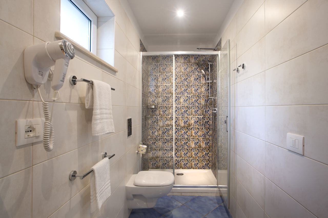Bagno con doccia, toilette e asciugacapelli a parete.