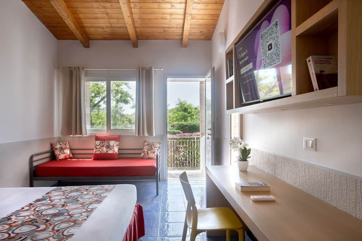 A room with a bed, a sofa, a desk, and a balcony.