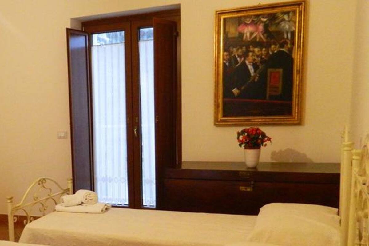 Hotelkamer met twee bedden, een schilderij aan de muur, een vaas met bloemen en een afstandsbediening op het nachtkastje.