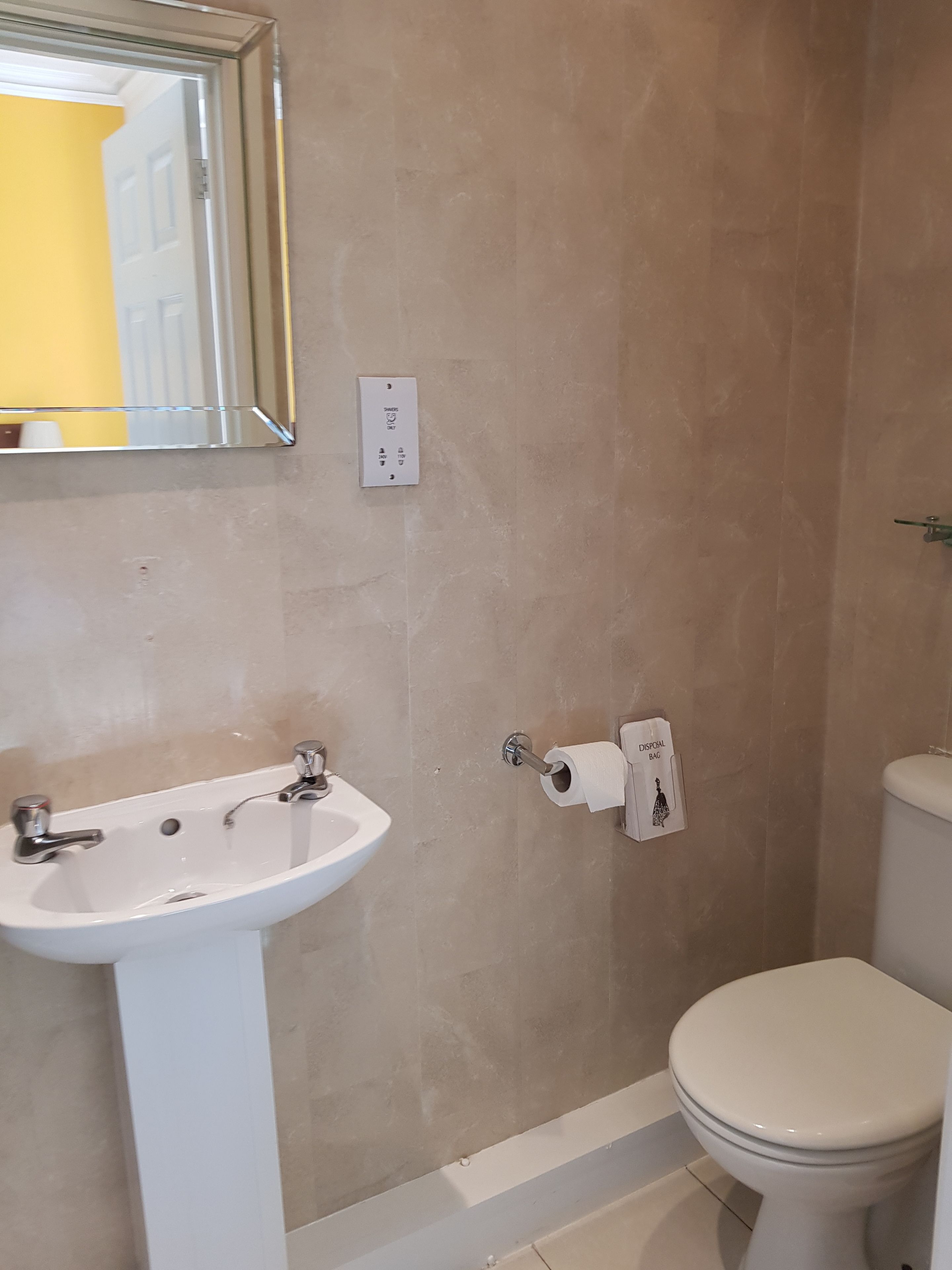 A bathroom with a white sink, toilet, and a mirror.