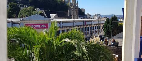 A view of a cityscape with a prominent church spire, a bowling alley, and lush greenery.