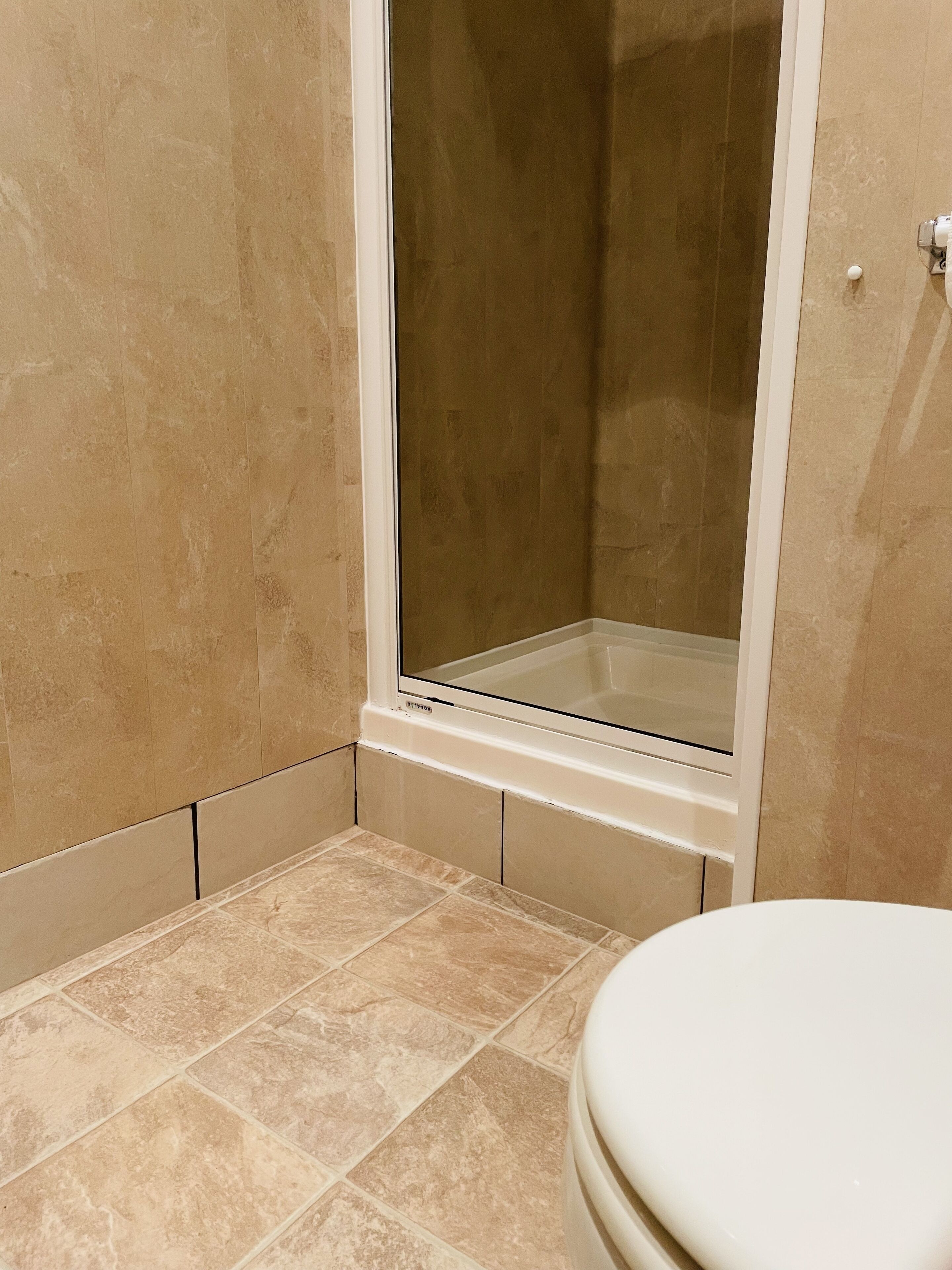 Une salle de bain avec une douche, des toilettes et un carrelage au sol.