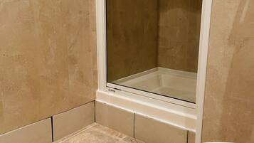 Une salle de bain avec une douche, des toilettes et un carrelage au sol.