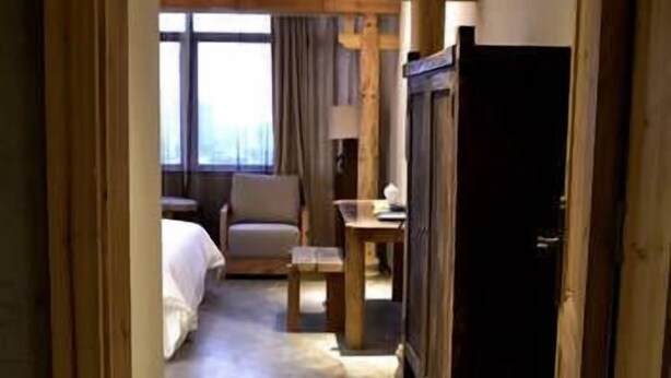 A hotel room with a bed, a desk, a chair, and a television. - Chenxi Fengqing Hotel (Zhaoqing)