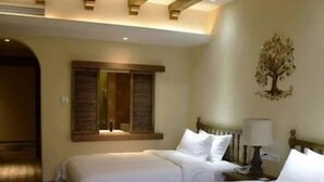 A hotel room with two beds, wooden beams on the ceiling, a tree mural on the wall, and a window with shutters. - Chenxi Fengqing Hotel (Zhaoqing)