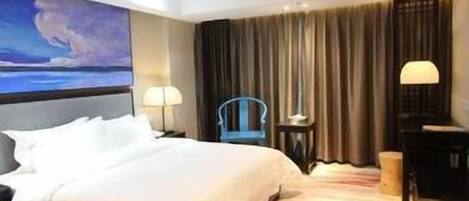 Ein Hotelzimmer mit einem großen Bett, einem Schreibtisch, einem Sessel und einem Bild an der Wand.