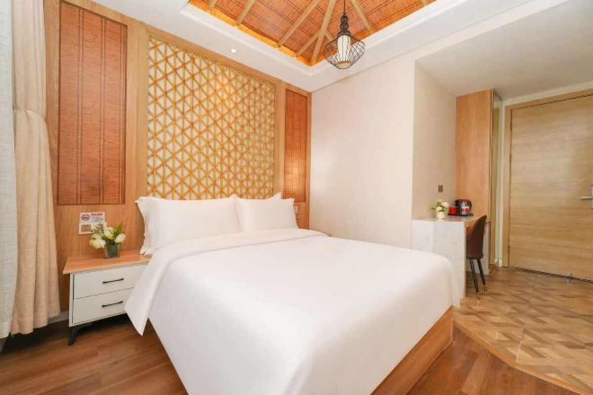 A hotel room with a large bed, wooden paneling, a desk with a chair, and a wardrobe.