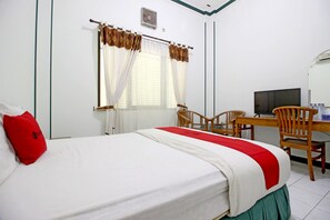 Una habitación de hotel con una cama, un escritorio con silla, un televisor y una ventana con cortinas.