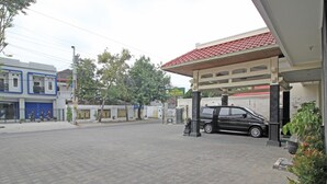 Entrada de un hotel con zona de estacionamiento techada, un cartel de Hotel Cinka Garini y un coche negro aparcado cerca.