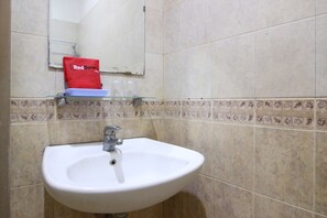 Une salle de bain avec un lavabo blanc, un miroir et une serviette rouge accrochée au mur.
